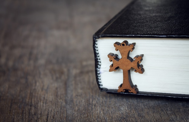 Croix et Bible sur fond de bois.