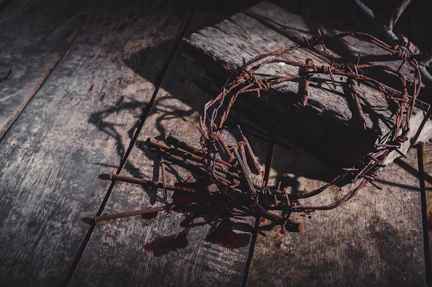 Croix en bois avec couronne d'épines et pointes sanglantes sur fond sombre