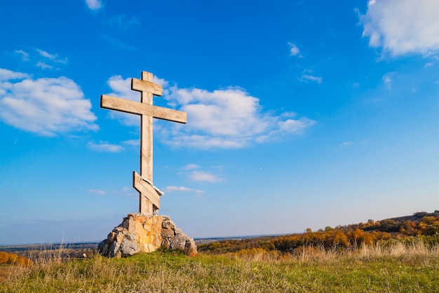 Croix en bois religieuse sur une colline contre le ciel bleu