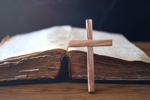 Croix chrétienne en bois sur la Sainte Bible sur table en bois