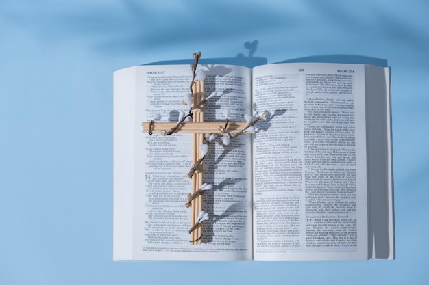 Croix décorée de fleurs avec la Sainte Bible sur fond bleu concept minimaliste de vacances de Pâques