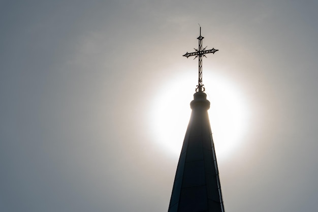 La croix sur la flèche de l'église sur fond de soleil Le halo du soleil encadre magnifiquement la croix de l'église