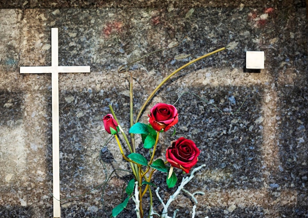 Photo une croix et des fleurs sont sur un mur.