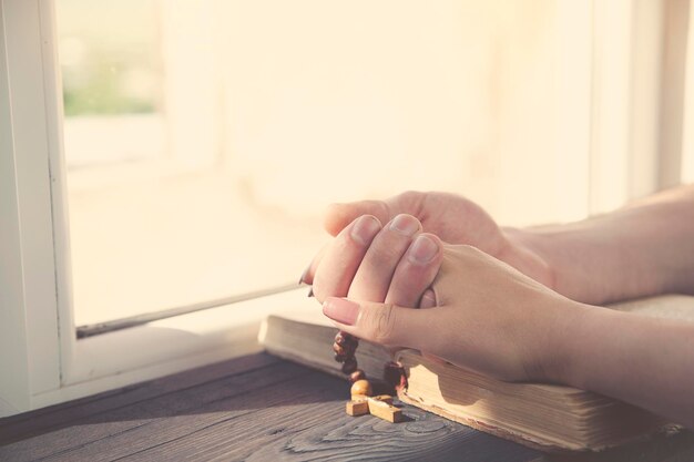 Croix sur les mains de couples sur le fond en bois