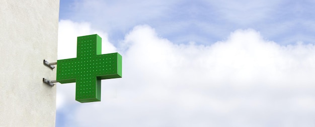 Photo croix médicale brillante verte indiquant l'emplacement d'une pharmacie sur une bannière médicale de rue
