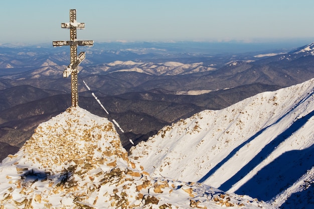 Croix de métal chrétienne au sommet d'une montagne, paysage de montagne d'hiver.