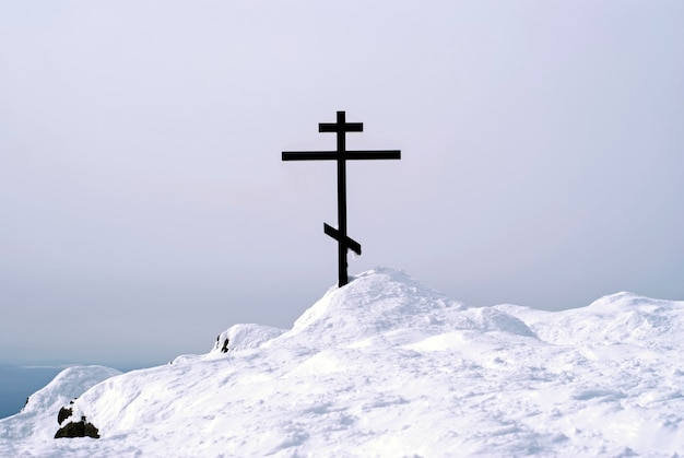 Croix orthodoxe au sommet du mont Konzhakovskiy Kamen contre les montagnes d'hiver environnantes