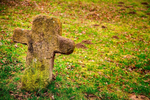 Croix de pierre de symbole de religion de christianisme dans le cimetière et l'herbe