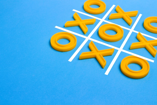 Croix en plastique jaune et un orteil et un champ réglé pour jouer au tic-tac-toe sur fond bleu. Concept XO Win Challenge. Jeu éducatif pour les enfants