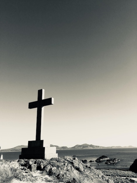 Croix sur le rocher contre un ciel clair au coucher du soleil