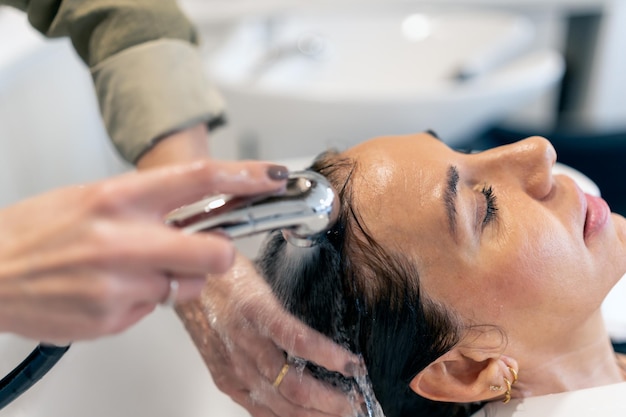 Crop coiffeur laver les cheveux du client avec de l'eau