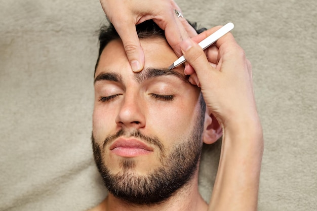 Crop femme épilant les sourcils de l'homme