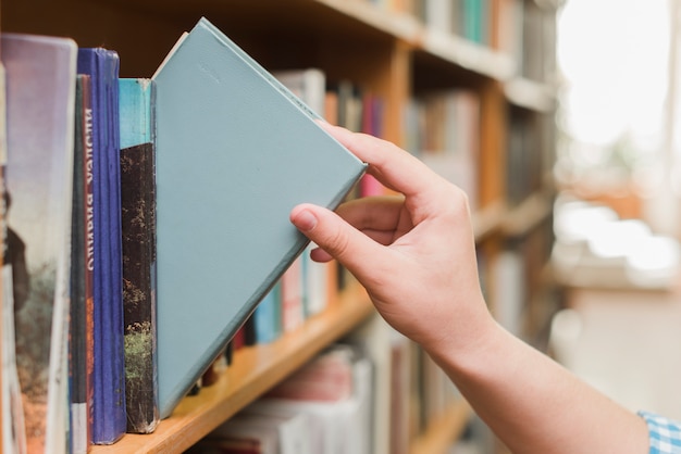 Crop main prenant le livre de l&#39;étagère