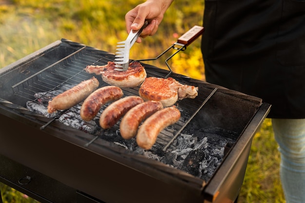 Crop mâle grillant de la viande et des saucisses