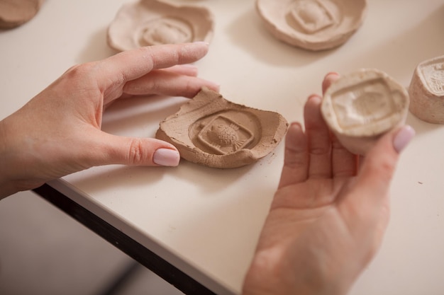 Cropped close up of female potter hands holding figurines en argile