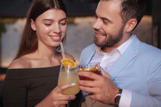 Cropped close up of happy young couple tinter des verres à cocktail, profiter de boissons au bar