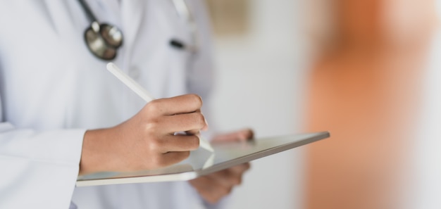 Cropped shot fo jeune femme médecin travaillant sur les dossiers médicaux et les résultats des examens avec tablette