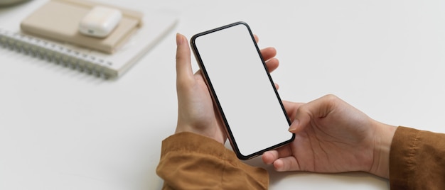 Cropped shot of female hands using smartphone with clipping path on office desk in home office