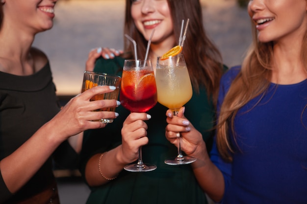 Cropped shot of happy female friends tinter des verres à cocktail ensemble, célébrer ensemble