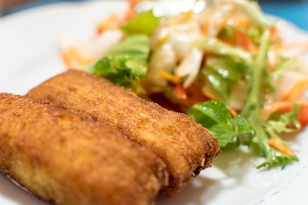 Croquette de pommes de terre remplies de fromage et d'herbes servies avec des tomates de salade vertes fraîches et du poivre