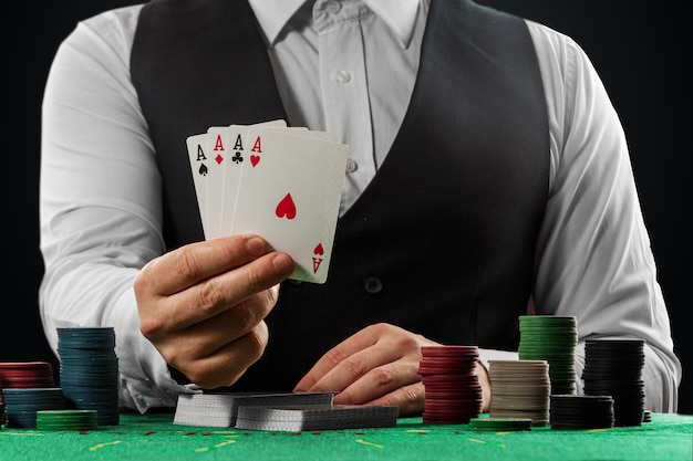 Croupier mâle dans le casino à la table les mains en gros plan. Concept de casino, jeux de hasard, poker, jetons sur la table verte du casino.