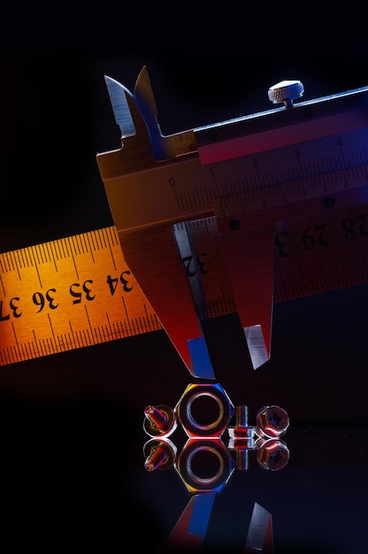 Écrous métalliques chromés de différentes tailles et un pied à coulisse mesurant l'écrou Fond noir
