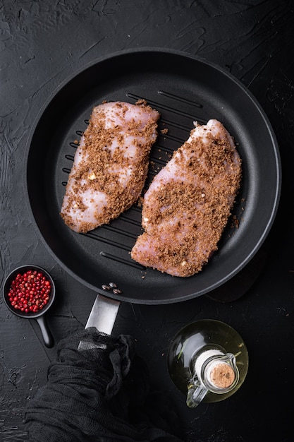 Croustillant de poulet à l'ail ingrédient cru sur poêle en fonte sur table noire, mise à plat