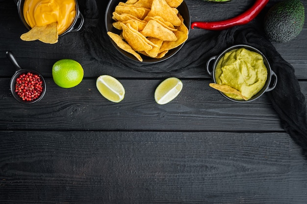 Croustilles de maïs nachos avec sauce trempette traditionnelle, sur table en bois noir, vue de dessus ou mise à plat