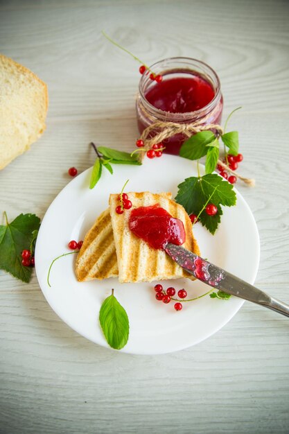 Photo croûtons de pain frit pour le petit déjeuner avec de la confiture de groseille dans une assiette avec des baies sur une table en bois