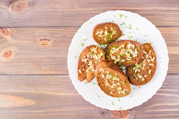 Croûtons de seigle à l'ail frais à l'aneth sur une assiette sur une table en bois