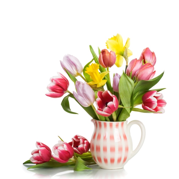 Cruche avec des fleurs de printemps sur fond blanc