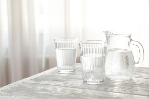 Cruche et verres d'eau sur une table en bois blanche