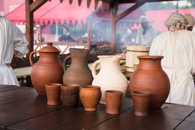 Une cruche à vin et un ensemble de tasses en argile sur la table en bois.