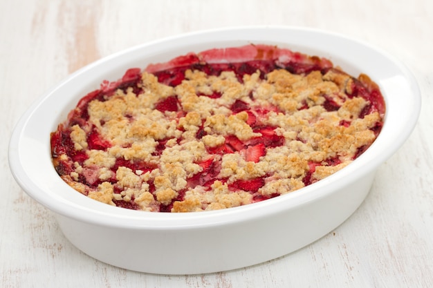 Crumble aux fraises et aux flocons d'avoine dans un plat blanc en bois blanc