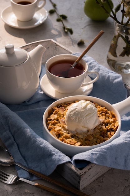 Crumble aux pommes avec une boule de glace à la vanille et du thé sur un plateau en bois. Concept de petit déjeuner.