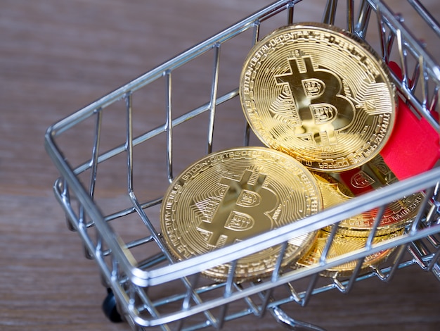 Crypto-monnaie bitcoin doré dans le panier rouge sur le bois de bureau.