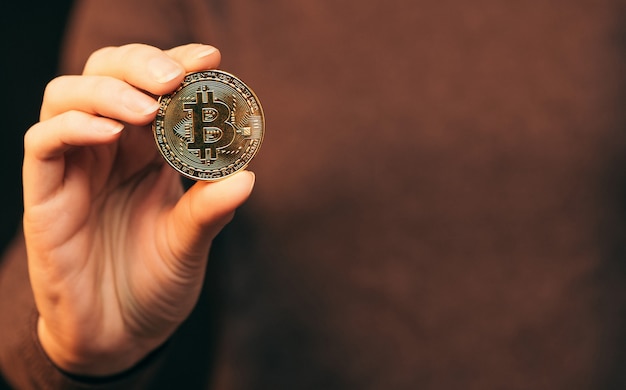Crypto-monnaie Bitcoin pièce d'or. Tenant en main le symbole de la crypto-monnaie.
