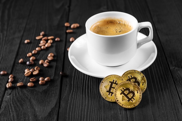 Crypto-monnaie doré bitcoin debout sur une tasse de café isolé