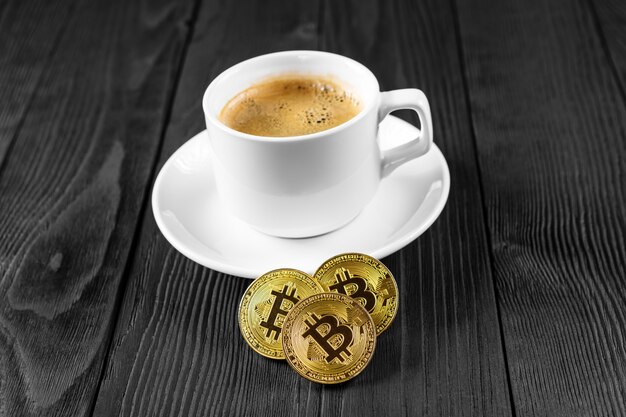 Crypto-monnaie doré bitcoin debout sur une tasse de café