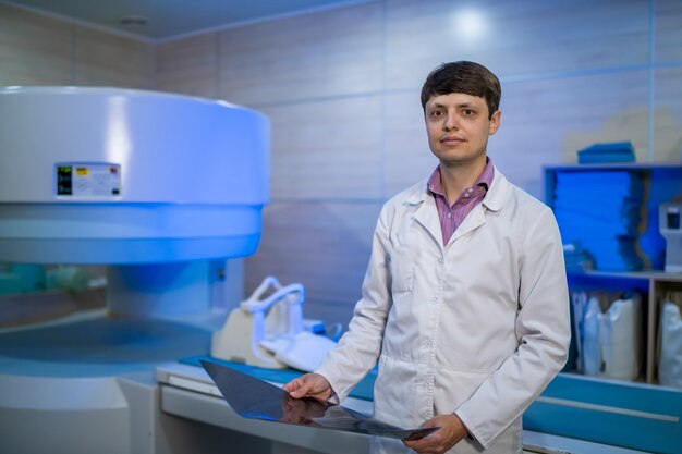 CT médical ou IRM ou PET Scan debout dans le laboratoire de l'hôpital moderne. Radiologue tenant une radiographie dans les mains.