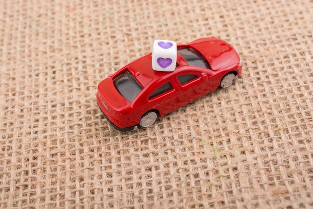 Photo cube d'amour sur une petite voiture rouge sur une toile de lin