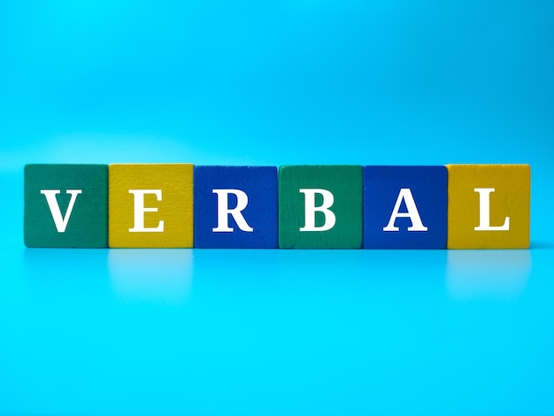 Cube en bois coloré avec le mot VERBAL sur fond bleu