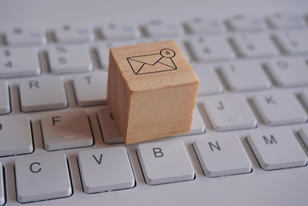 Cube en bois avec une nouvelle icône de notification par courrier électronique au-dessus du clavier Concept de communication et de technologie