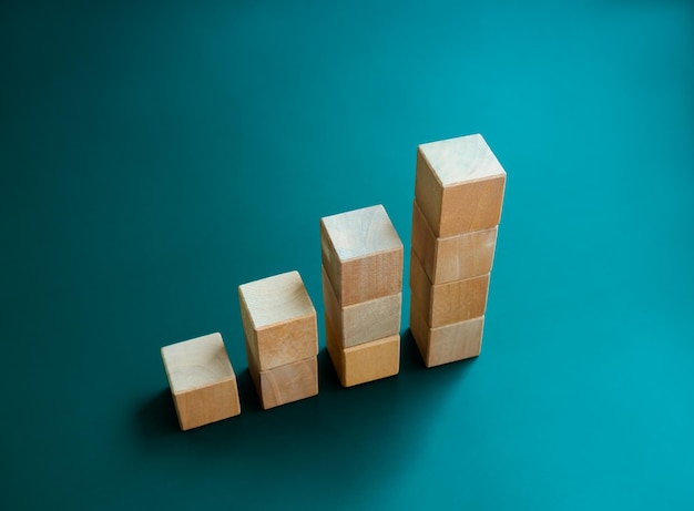 Cube en bois vierge bloque les étapes du graphique à barres isolées sur fond bleu foncé Tendances des revenus d'investissement Inflation Croissance des entreprises Concepts d'amélioration économique Graphique en bois de style écologique en quatre étapes