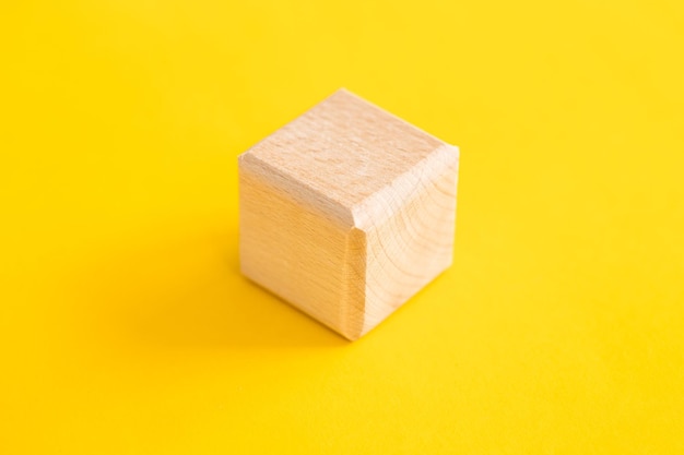 Cube de formes géométriques en bois isolé sur un jaune