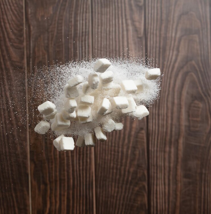 Photo cube de sucre dans le sac sac volant explosion de sucre de cristal blanc chute abstraite mouche pur sucre raffiné cubes sac éclaboussure dans l'air nourriture objet de conception bois cuisine arrière-plan mouvement de congélation à grande vitesse
