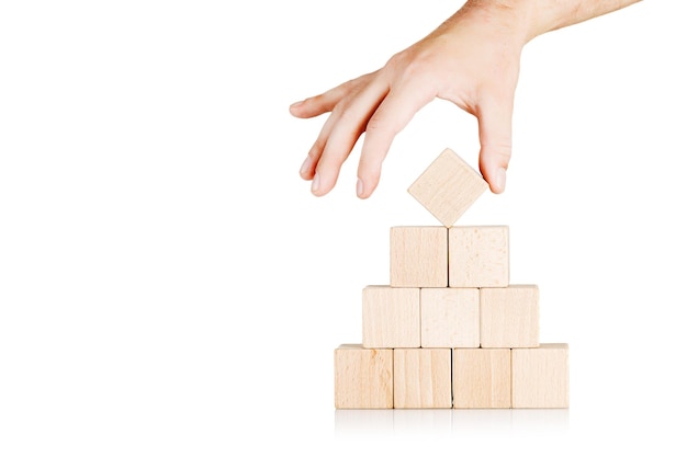 des cubes de bois en forme de pyramide avec une main sur un fond blanc isolé en gros plan