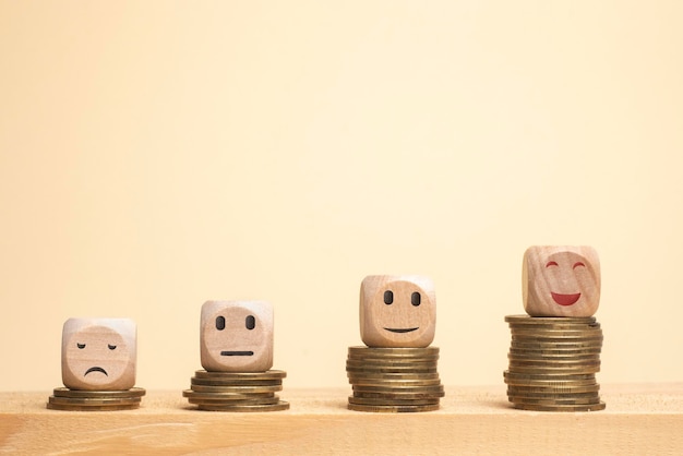 Cubes en bois avec icône visage smiley sur pile de pièces en forme d'escalier concept de satisfaction financière réussite financière