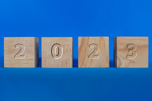 Cubes en bois avec l'inscription 2023 gravée dans le bois sur fond bleu