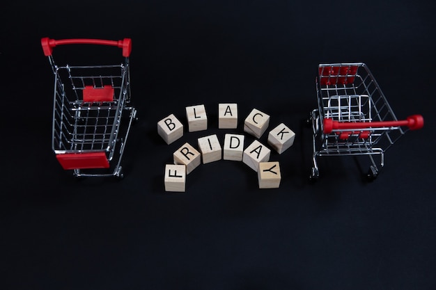 Cubes en bois avec l'inscription-Black Friday entre deux chariots de supermarché